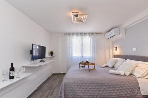 um quarto branco com uma cama e uma televisão em Double room with pool 2261 em Medulin