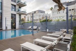 a swimming pool with chaise lounge chairs next to a building at Art and Luxe in Tel Aviv