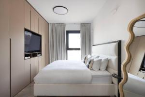1 dormitorio con 1 cama blanca y TV en Art and Luxe, en Tel Aviv