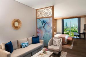 Taj Jumeirah Lakes Towers في دبي: غرفة معيشة مع أريكة وسرير