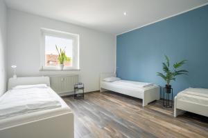 een witte kamer met 2 bedden en een raam bij XXL Superior Apartment 2 - 9 Personen in Castrop-Rauxel