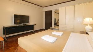 a bedroom with a bed and a flat screen tv at El Rico Suite Makati by RedDoorz in Manila