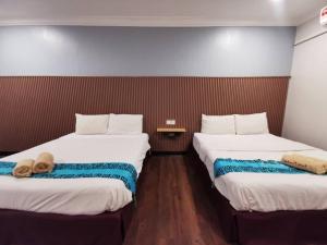 two beds in a hotel room with a teddy bear between them at Shell Out Cenang Beach Resort in Pantai Cenang