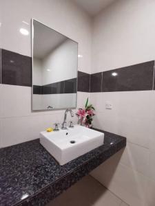 a bathroom with a white sink and a large mirror at Shell Out Cenang Beach Resort in Pantai Cenang