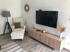 ein Wohnzimmer mit einem Flachbild-TV und einem Stuhl in der Unterkunft SBM Apartman in Balatonfüred