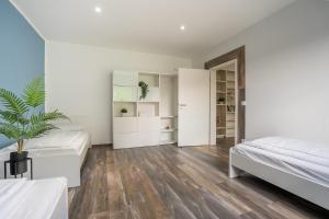 a white bedroom with two beds and a potted plant at XXL Superior Apartment 2 - 9 Personen in Castrop-Rauxel