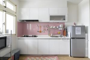 a pink kitchen with white cabinets and a refrigerator at 乘風之旅溫馨包層華廈每日只接待一組客人最多6人 in Yilan City