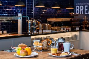 una mesa con dos platos de comida y fruta. en Premier Inn Lübeck City Stadtgraben, en Lübeck