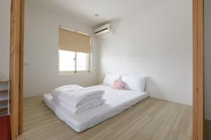 a bedroom with a bed with white sheets and a pink pillow at 乘風之旅溫馨包層華廈每日只接待一組客人最多6人 in Yilan City