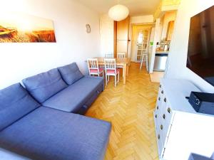 a living room with a blue couch and a kitchen at Great apartament, near forest and with sea view in Sopot