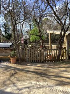 una valla de madera frente a una casa con árboles en Duplex (5pers) dans village vacances en Ardèche, en Grospierres
