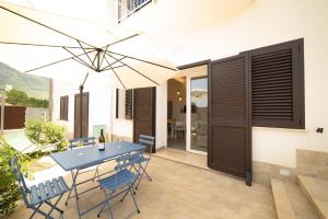eine Terrasse mit einem Tisch, Stühlen und einem Sonnenschirm in der Unterkunft Blu Home Scopello in Castellammare del Golfo
