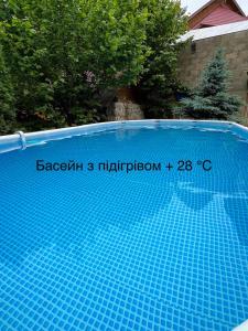 a blue swimming pool with a sign on it at Кам'яний двір in Mykulychyn