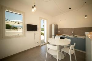 a kitchen with a white table and white chairs at Scopello - Luxury Residence con piscina - 5 minuti dal mare in Castellammare del Golfo