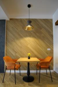 a dining room table with orange chairs and a light fixture at Pensiunea Magic in Băile Govora