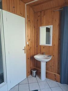 a bathroom with a sink and a wooden wall at Maisonnette Pont de l’Arche in Pont-de-lʼArche +9 photos