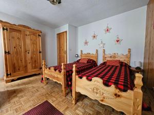 a bedroom with two wooden beds and a wooden cabinet at Appartamento panoramico La Chapelle in Torgnon