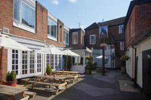 a patio with tables and umbrellas in front of buildings at Bear Hotel by Greene King Inns in Havant