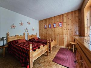 a bedroom with two beds and wooden walls at Appartamento panoramico La Chapelle in Torgnon