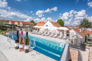a row of wine glasses and wine bottles next to a swimming pool at Resort Valtberg - Depandance in Valtice