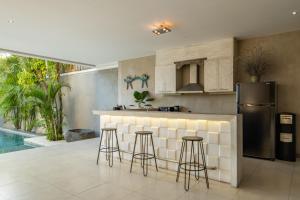 a kitchen with a bar with stools and a refrigerator at Spacious and Stylish Villa 3 Bedroom Seminyak in Denpasar