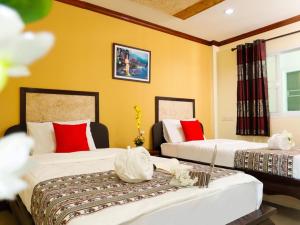 Duas camas num quarto com paredes amarelas em AIRBEST Explore Chiang Rai Hotel em Chiang Rai