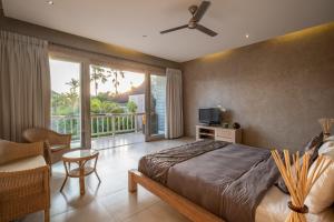 a bedroom with a bed and a tv and a balcony at Spacious and Stylish Villa 3 Bedroom Seminyak in Denpasar