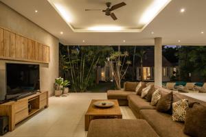 a living room with a couch and a flat screen tv at Spacious and Stylish Villa 3 Bedroom Seminyak in Denpasar