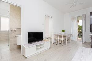 een witte woonkamer met een tv en een tafel bij Villa Graziano in Cesenatico