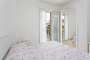 een witte slaapkamer met een bed en een groot raam bij Villa Graziano in Cesenatico