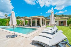 une villa avec une piscine et deux parasols blancs dans l'établissement Villa Sa Olivera, à Crestatx