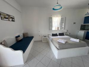 ein weißes Zimmer mit 2 Betten und einem Sofa in der Unterkunft Christos rooms milos in Adamas