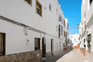 um beco vazio com edifícios brancos e um céu azul em Casa Morales 2 em Conil de la Frontera