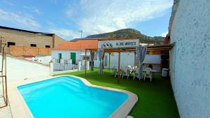 a swimming pool in front of a building with a table and chairs at Aljibe Morisco - Casa Rural - in Hornachos