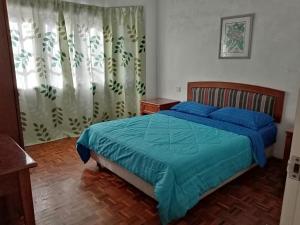 een slaapkamer met een bed met een blauw dekbed bij Pretty Bear Homestay in Cameron Highlands