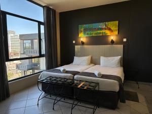 N1 Hotel Samora Machel Harare في هراري: غرفة نوم بسرير كبير ونافذة كبيرة