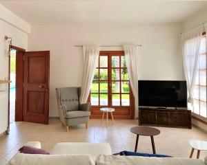 ein Wohnzimmer mit einem TV, einem Sofa und einem Stuhl in der Unterkunft George's gorgeous house Anavysos in Anavyssos