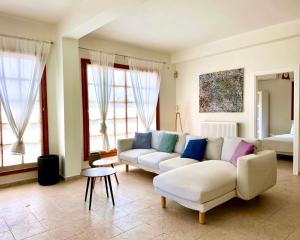 ein Wohnzimmer mit einem weißen Sofa und einigen Fenstern in der Unterkunft George's gorgeous house Anavysos in Anavyssos