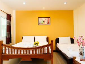 two beds in a room with yellow walls at AIRBEST Explore Chiang Rai Hotel in Chiang Rai