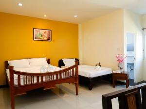 a bedroom with two beds and a table with flowers at AIRBEST Explore Chiang Rai Hotel in Chiang Rai