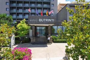 Hotel Butrinti & SPA في سارنده: مبنى الفندق مع وجود لافته مكتوب عليها buttrint