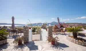 eine Terrasse mit Tischen und Stühlen und Meerblick in der Unterkunft Christos rooms milos in Adamas