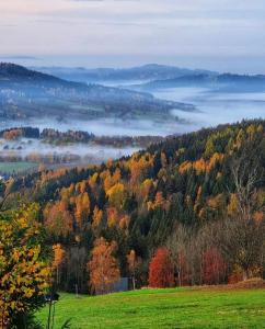 een uitzicht op een vallei met herfstbomen en mist bij Premium Apartment Rokytnice in Rokytnice nad Jizerou