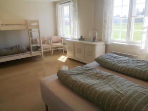 a bedroom with two beds and a chair and windows at Frogner Hovedgård in Skien