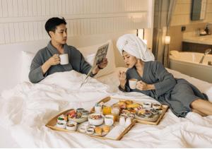 a man and woman sitting in bed with a tray of food at SYN Boutique Hotel in Chiang Mai