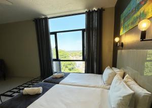 Un dormitorio con dos camas y una gran ventana. en N1 Hotel Samora Machel Harare, en Harare