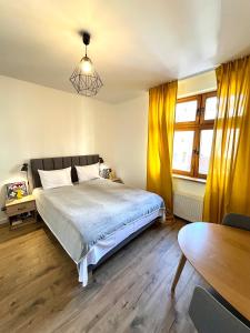 シュチェチンにあるOld Town Szczecinのベッドルーム1室(黄色いカーテンとテーブル付きのベッド1台付)