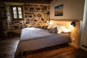 Bett in einem Zimmer mit einer Steinmauer in der Unterkunft Les Terres Nères in Aucun