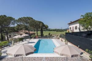 a swimming pool with umbrellas and a building at Anita in Colle di Val d'Elsa