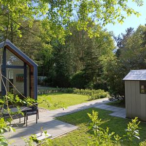 a garden with a bench and a small shed at Huisje Bloemendal in Balkbrug